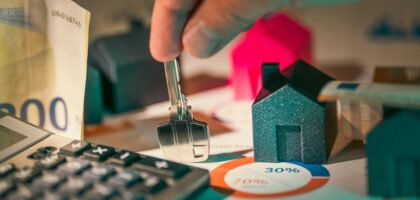 A close-up of real estate financial planning with keys, calculator, and money.