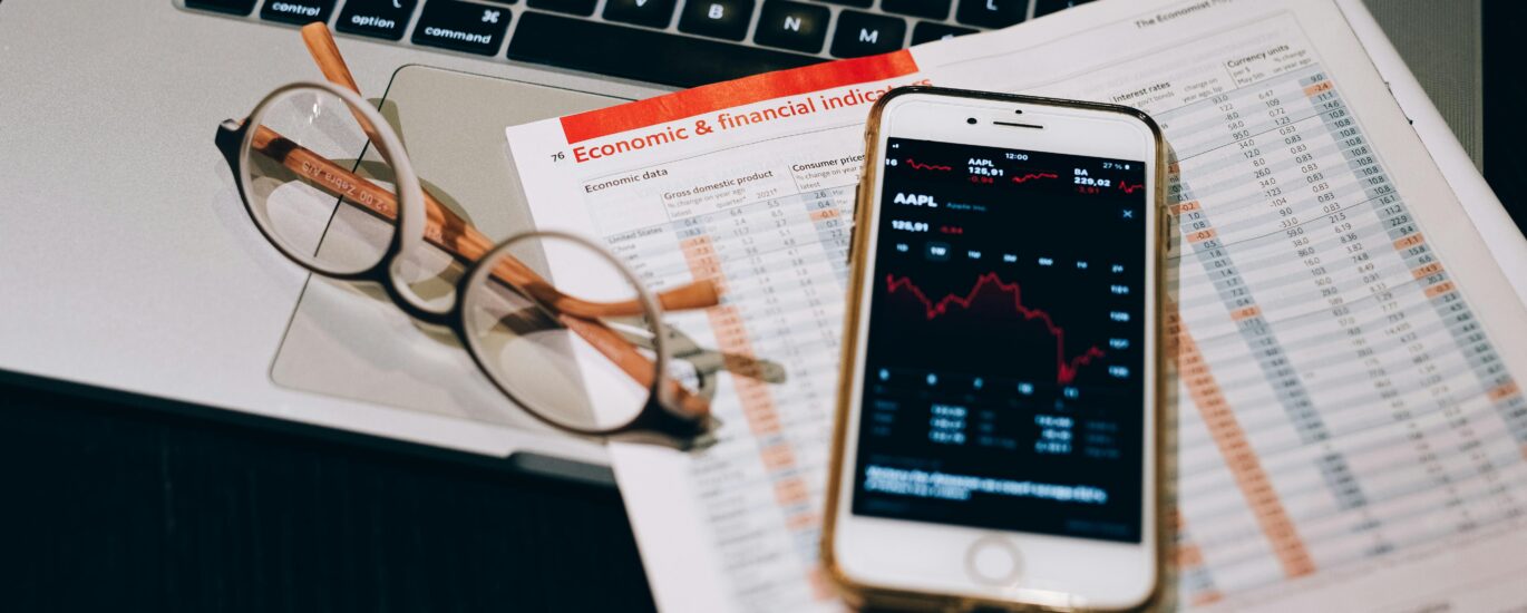 A detailed look at financial tools including a smartphone and laptop for stock analysis.